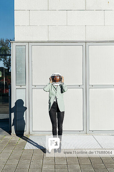 Businesswoman with space helmet jumping in front of office building