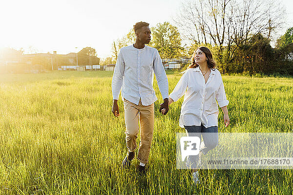 Young couple holding hands walking on grass