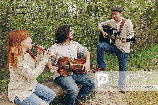 Folk music group with musical instruments discussing with each other near bench at roadside