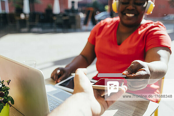 Zufriedener Kunde  der im Straßencafé kontaktlos per Kreditkarte bezahlt