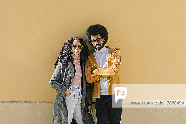 Couple wearing sunglasses standing in front of wall