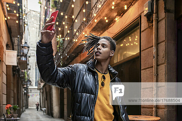 Young man taking selfie through mobile phone in alley