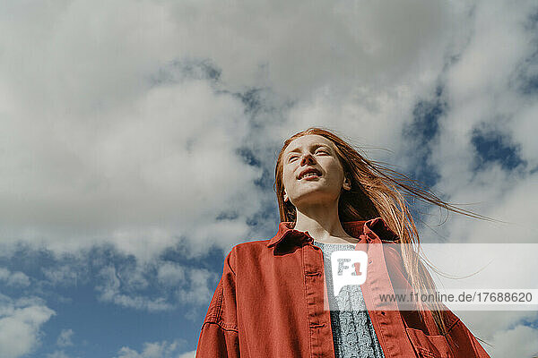 Young woman standing under cloudy sky
