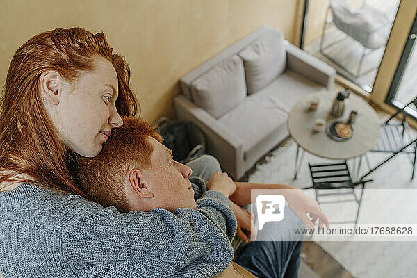 Young woman embracing boyfriend from back sitting in living room