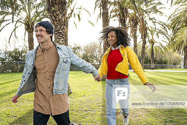 Happy man with girlfriend running at park