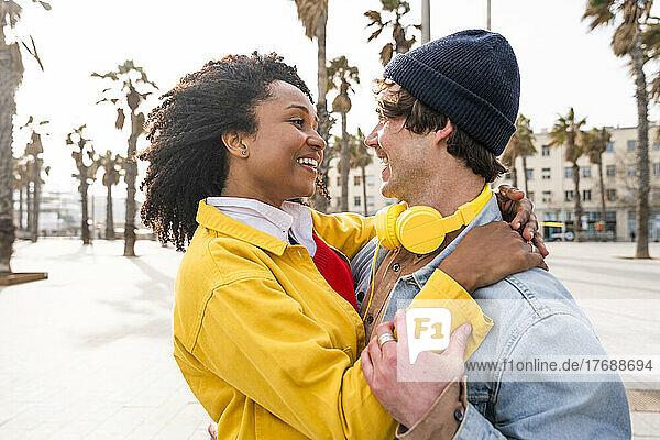 Lächelnde Frau mit Afro-Frisur blickt Mann mit Strickmütze an