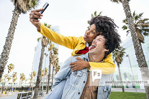 Couple sticking out tongues taking selfie through smart phone