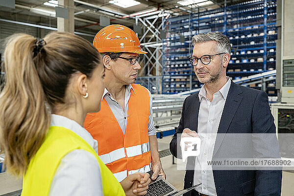 Mature businessman planning strategy with colleagues in warehouse