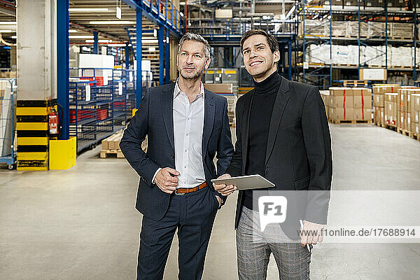 Confident businessman with smiling colleague at factory