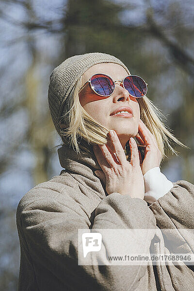 Blond woman wearing knit hat and sunglasses on sunny day