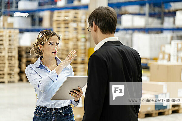 Young businesswoman holding tablet PC with colleague at factory