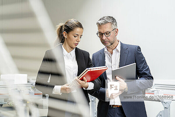 Mature businessman discussing with young businesswoman over diary in warehouse
