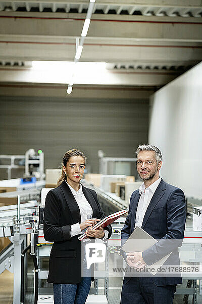 Confident businesswoman with mature businessman at warehouse