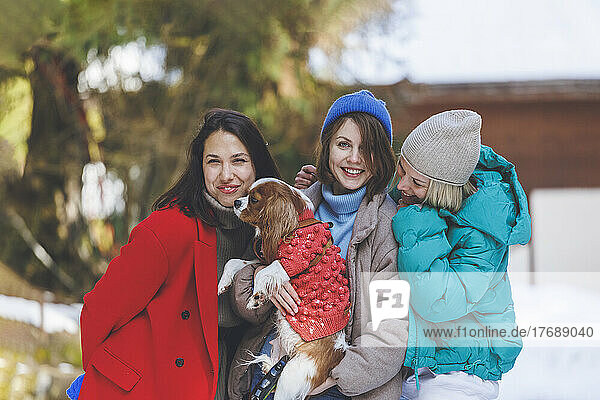 Happy women standing together with pet dog