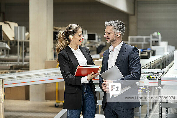 Happy businesswoman discussing with businessman in warehouse