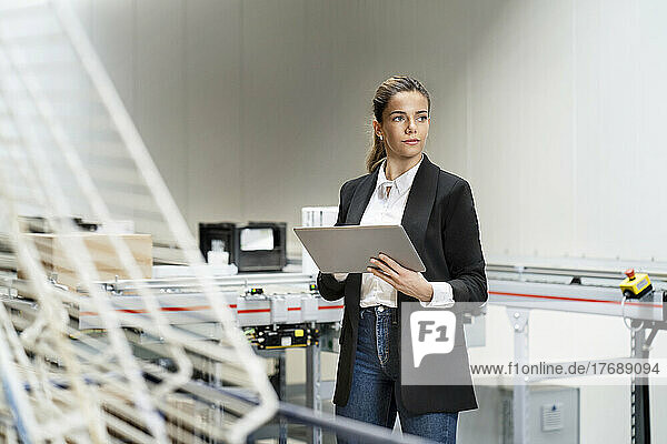 Thoughtful businesswoman with tablet PC in warehouse