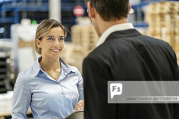 Smiling businesswoman discussing with colleague in warehouse