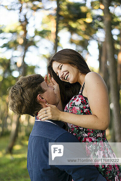 Young man lifting girlfriend enjoying in forest