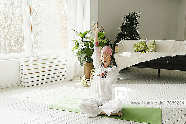 Frau macht Yoga im heimischen Wohnzimmer