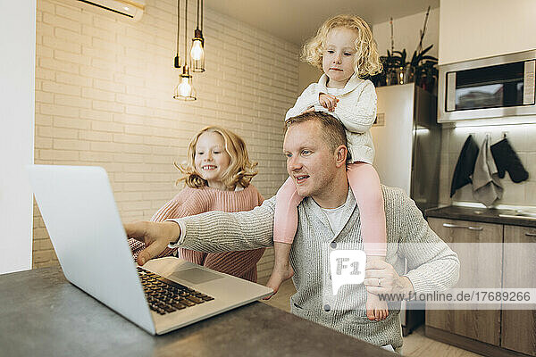 Vater arbeitet am Laptop  Tochter sitzt zu Hause auf der Schulter