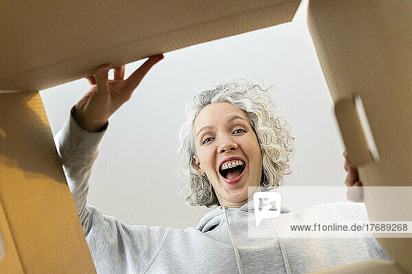 Glückliche Frau öffnet Karton zu Hause