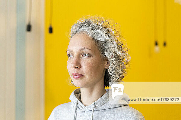 Woman with gray hair standing in front of yellow wall