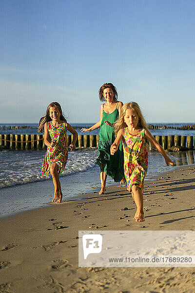 Happy mother with daughters running at beach