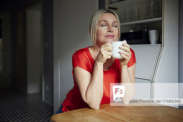 Mature woman with tea cup sitting at table
