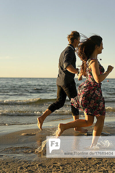 Young couple running at beach on sunny day