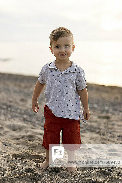 Smiling baby boy standing at beach
