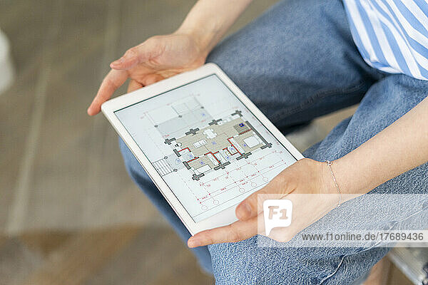 Woman examining blueprint of home on tablet PC