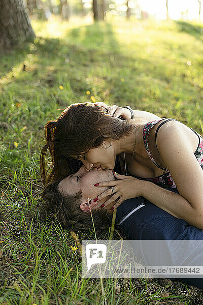 Happy couple kissing each other lying on grass
