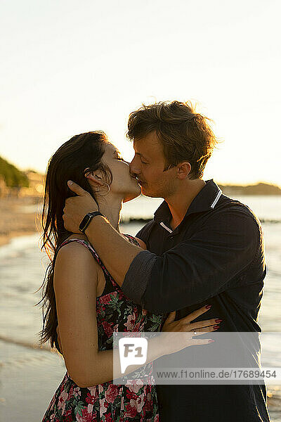 Zärtliches junges Paar küsst sich an einem sonnigen Tag am Strand