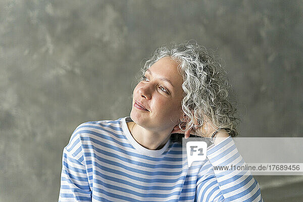 Smiling woman with gray hair in front of wall