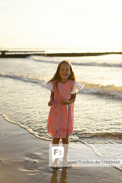 Happy girl standing in front of sea at beach
