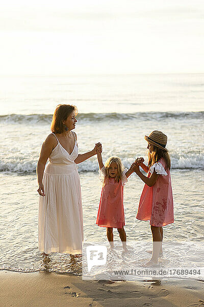Happy mother and daughters having fun at beach