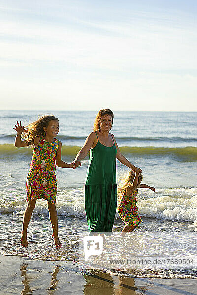 Smiling mother with daughters enjoying at beach