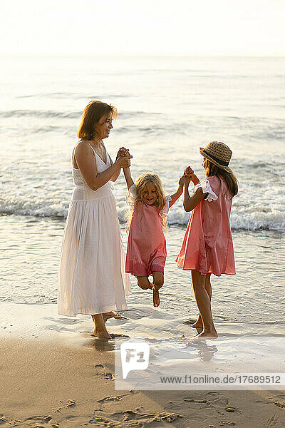 Playful mother and daughter enjoying with girl at beach