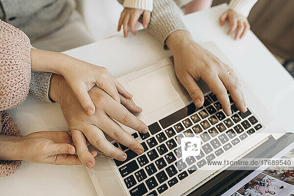 Hands of businessman working on laptop with daughters