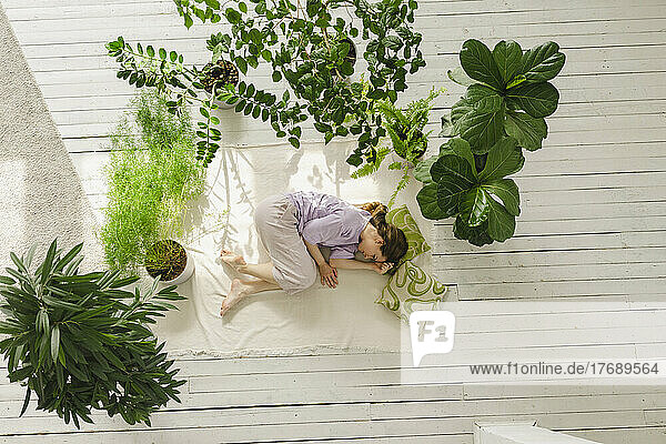 Woman relaxing amidst potted plants at home