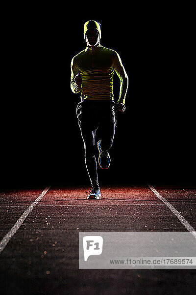 Junger Mann joggt nachts auf der Laufstrecke