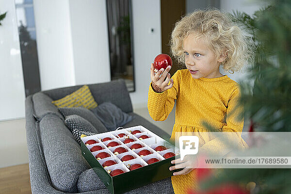 Blond girl looking at bauble in living room at home