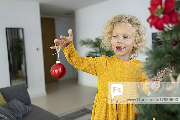 Blond girl looking at Christmas ornament at home
