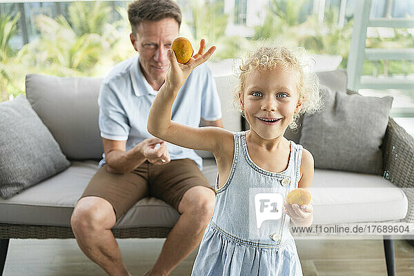 Happy girl showing Easter eggs in front of father at home