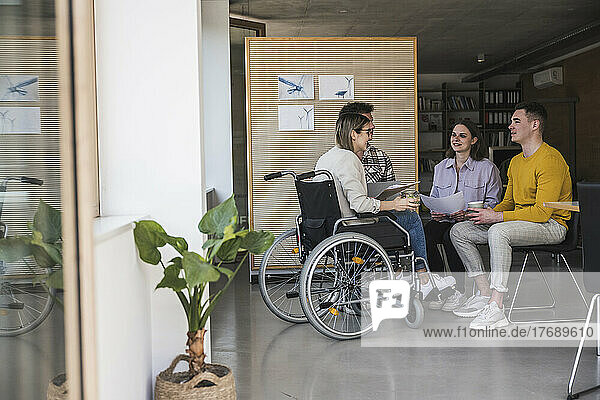 Young business people having a meeting in office with woman sitting in wheelchair