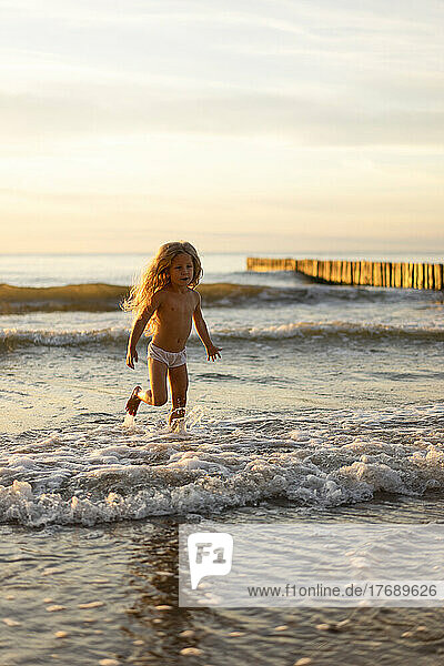 Cute girl wearing underwear playing in water on beach