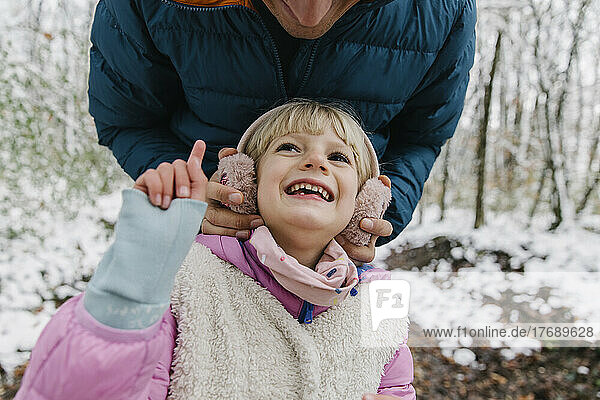 Playful girl with father in winter forest