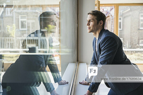 Businessman looking out of window in office