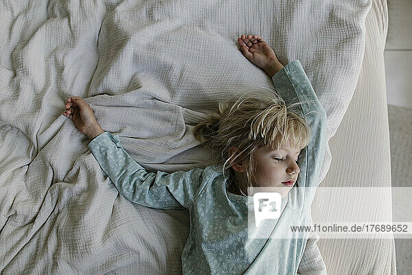Girl with blond hair sleeping on bed at home