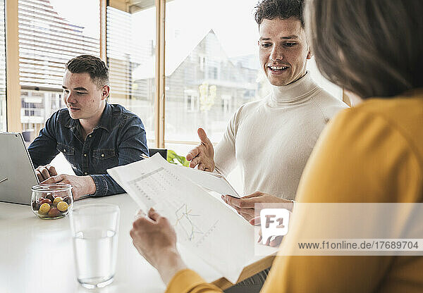 Young business people discussing a document during a meeting in office